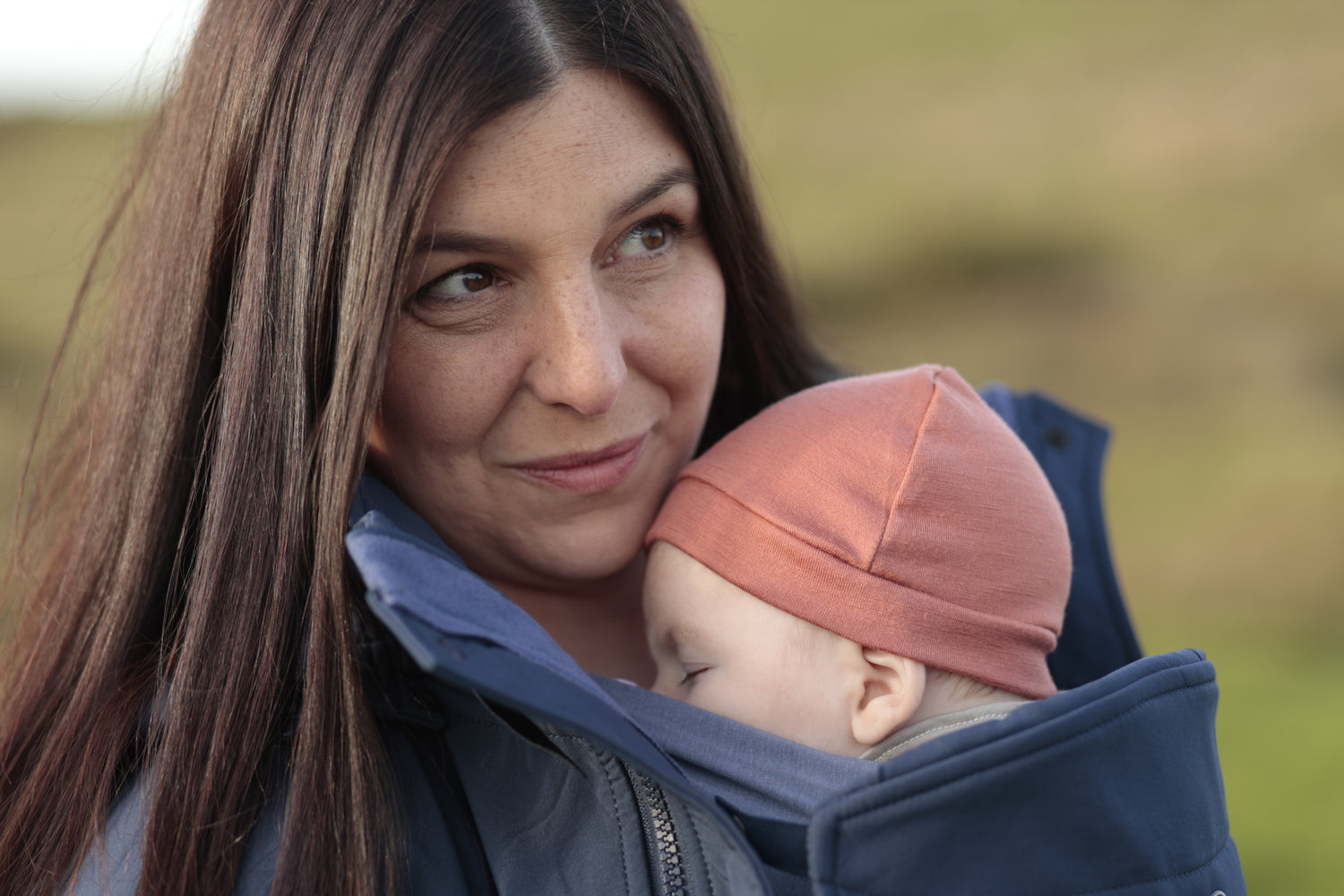 Baby wearing soft pink wool hat snuggled into mother&