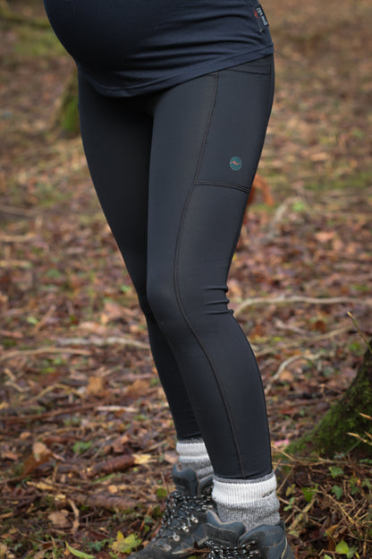 Full length shot of black maternity leggings, worn by woman standing in woodland wearing chunky socks and hiking boots